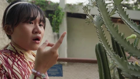 Ouch! Curious Girl Touches A Sharp Cactus Plant And Pokes Her Finger. Stock Footage 289086185