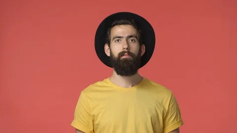 Ouch thats rough. Handsome upset bearded middle-eastern guy in black hat, yellow Stock Footage 115780527