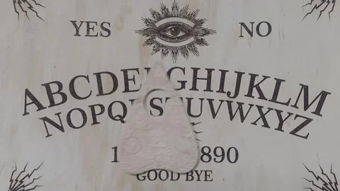 Ouija board's pointer moves on its own and writes the word spiritism Video stock 276685894