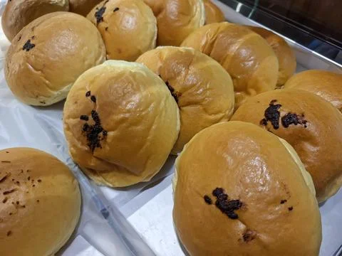 Ound golden soft bread rolls with small chocolate marks on top displayed cl.. Stock Photos