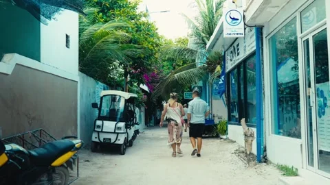 Ourists Walking Past Local Dive Shops and Golf Buggy on Sandy Street in Ukulhas Stock Footage 344106180