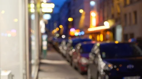 Out of focus background of cars parallel parked on city street next to shops Stock Footage 90033415