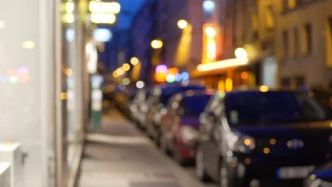 Out of focus background of cars parallel parked on city street next to shops Stock Footage 90033764