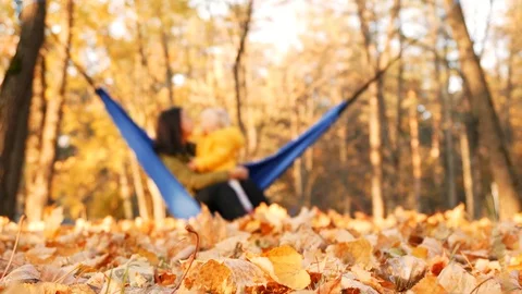 Out of focus background mother with her little daughter relaxing in hammock in Stock Footage 99144419