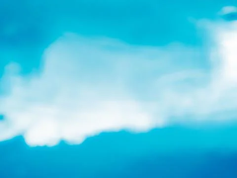 Out of focus bright white cloud against a vivid cyan and deep blue sky, dre.. 库存照片
