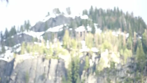 Out of focus to in focus: bright sun on snow covered top of Yosemite peak Stock Footage 241194105