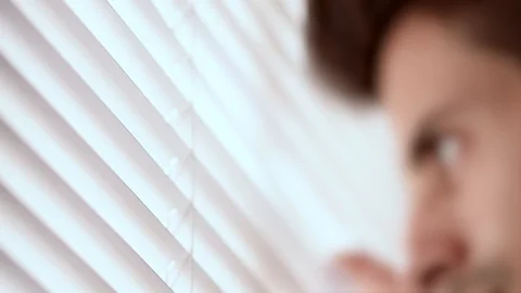 Out of focus, unidentifiable man looking through venetian Jalousie blinds Video stock 88928923