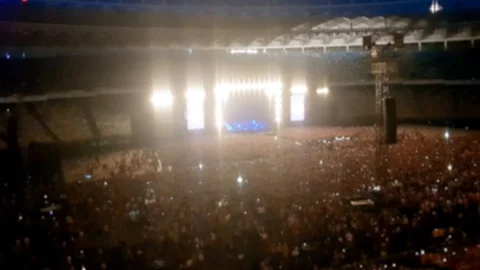 Out of focus video of brightly lit scene on concert at big stadium. Crowd is Stock Footage 107544546