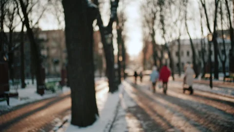 Out of focus view of people walking along a snowy park path during sunset Vídeos de archivo 329393592