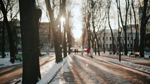 Out of focus view of people walking along a snowy park path during sunset Vídeos de archivo 329393773