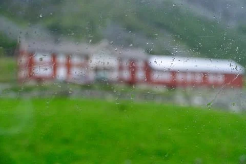 Out of focus view through rainy glass of red Scandinavian house 库存照片