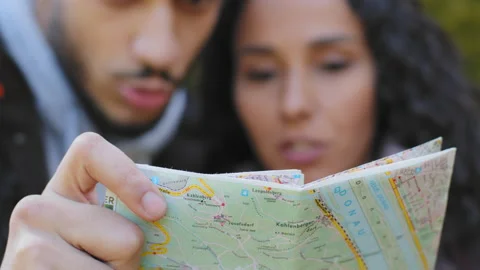 Out of focus young hispanic couple backpackers looking at paper map looking for Stock Footage 195306958