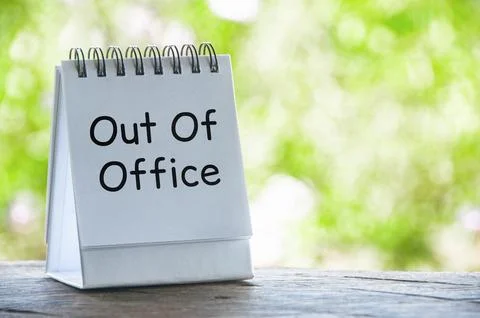 Out Of Office text on white notepad with bright green nature background. Va.. Stock Photos