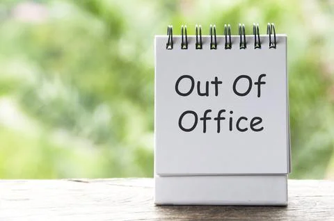 Out Of Office text on white notepad with blurred nature background Stock Photos