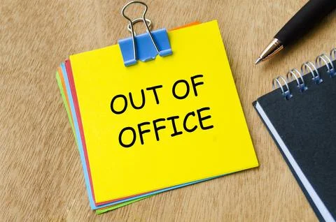 Out of office text on yellow notepad with pen and an notebook background. G.. Stock Photos