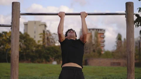 Out of shape - young man tries to do pull-ups on the bar without success Video stock 153983601