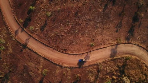 Outback winding red dirt road with blue ute driving aerial top down 動画素材 145709117