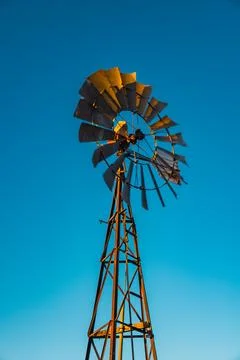 Outback windmill pumping water under blue sky at sunset Stock Photos