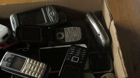 Outdated cell phones are in a big pile in a cardboard box. Video stock 128095191