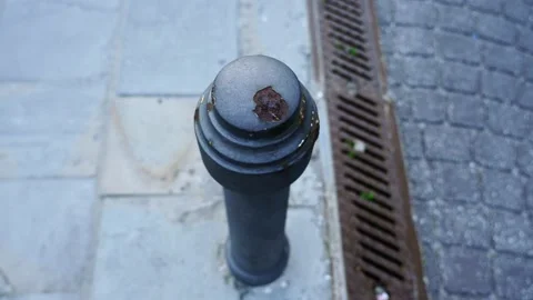 Outdated limiter pole located on sidewalk by brown drainage Stockbeeldmateriaal 150750578