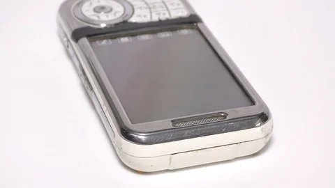 Outdated mobile phone on white surface and moving Stockbeeldmateriaal 111887804