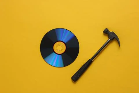 Outdated storage media. Hammer with CD discs on a yellow background Foto stock