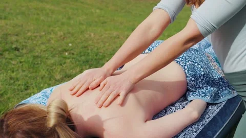 Outdoor back massage on a portable table in a grassy field, showing therapist 库存影片 336744302