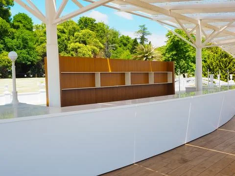 An outdoor bar with empty shelves and a white bar against a backdrop of green Stock Photos