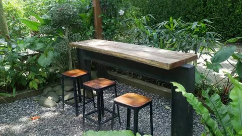 Outdoor bar table and stools in garden setting Stock Photos