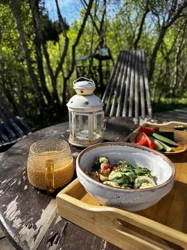 An outdoor breakfast or brunch setting on a rustic wooden table in a forest Stock Photos