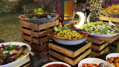 Outdoor buffet salad spread with lantern and crescent light at evening garden Stock Footage 329600562