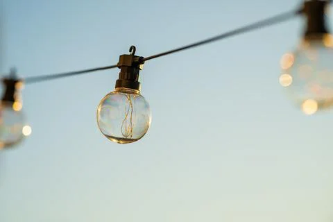 Outdoor bulb string light glowing at dusk. Stock Photos