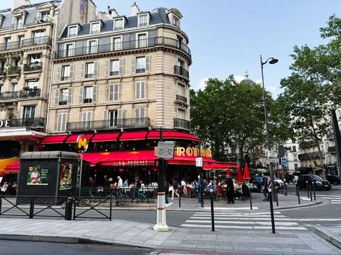 Outdoor caf scene at La Rotonde with red awnings and patrons on a Paris, Fr.. Stock Photos