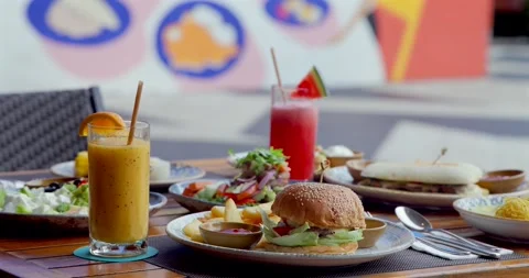 Outdoor cafe brunch includes fresh juice, burger, salad, sandwiches in Stock Footage 312001833