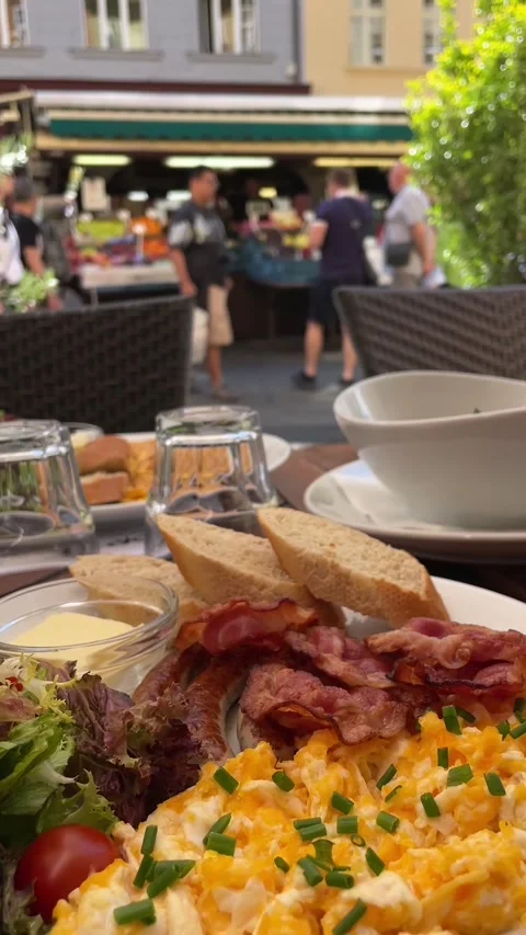 Outdoor cafe brunch table with plated salad eggs bacon and granola bowl under Vidéo 341626232