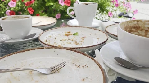 Outdoor cafe table with used coffee cups, saucers, plates, forks Stock Footage 346652098