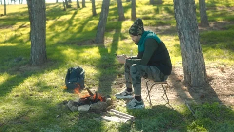 Outdoor Camper Checking Phone Next to Campfire Video stock 288668567