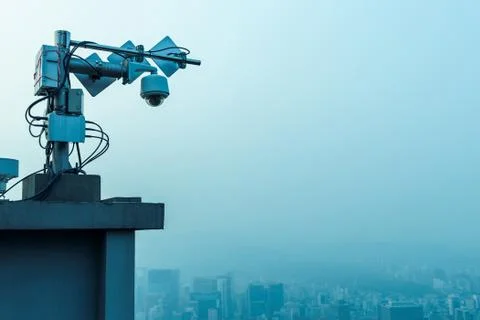 Outdoor CCTV security camera on high rise building rooftop in poor weather Stock Photos