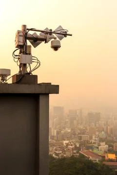 Outdoor CCTV security camera on high rise building rooftop in poor weather Stock Photos