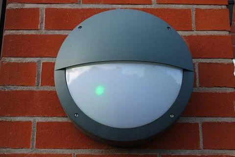 Outdoor Circular Grey light fitting attached to an external building, brick wall Fotos de archivo