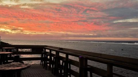 Outdoor deck overlooking an orange cloudy sky and sea Stock Photos