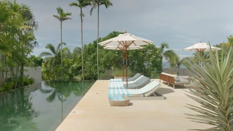 Outdoor deck, terrace with sun bed, umbrellas and towels near the swimming pool Stock Footage 229452276