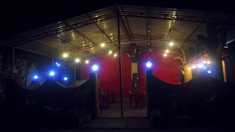 Outdoor dining area at night with bright ceiling lights and blue lamp posts.. Stock Footage 341347082