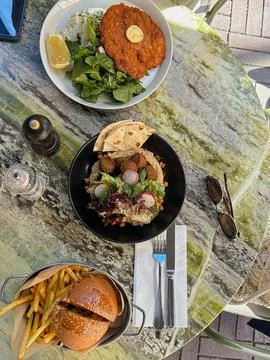 A outdoor dining scene featuring a crispy schnitzel, a falafel plate Stock Photos