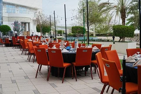 Outdoor dining setup with black tablecloths, orange chairs, elegant tableware Stock Photos