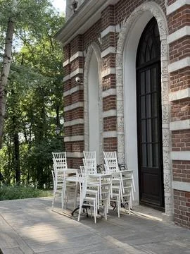 Outdoor dining setup with empty white chairs and table against historic bri.. Stock Photos