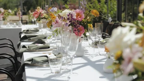 An outdoor dining table decorated with bright flowers and elegant glassware Stock-Footage 307918892