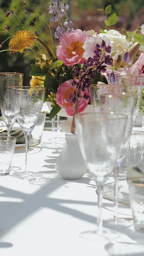 Outdoor dining table decorated with bright flowers and elegant glassware, close Stock-Footage 308398591