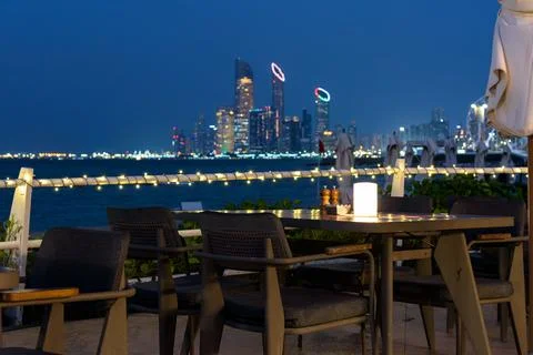 Outdoor dining table overlooking Abu Dhabi Corniche skyline at night Stock Photos