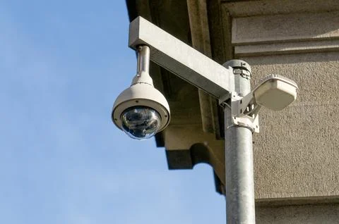 Outdoor dome security camera on building corner under blue sky Stock Photos